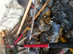 Back of one of four trucks, containing rakes and broken concrete.